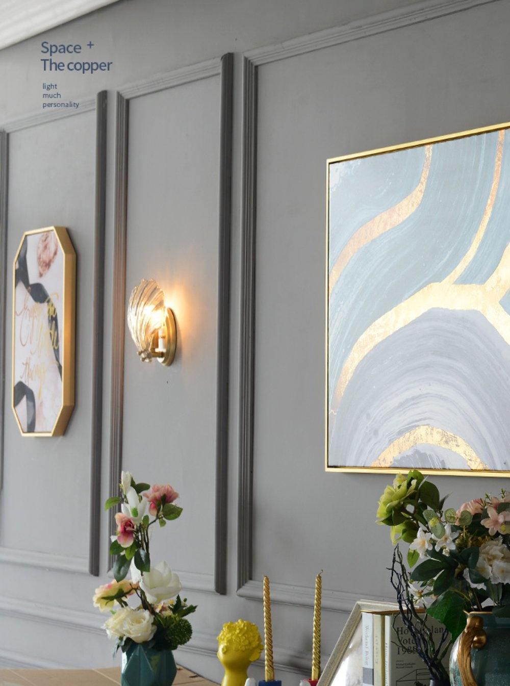 Between gold-framed art prints and vases of flowers, this Clérachic wall light glows on a panelled grey wall.