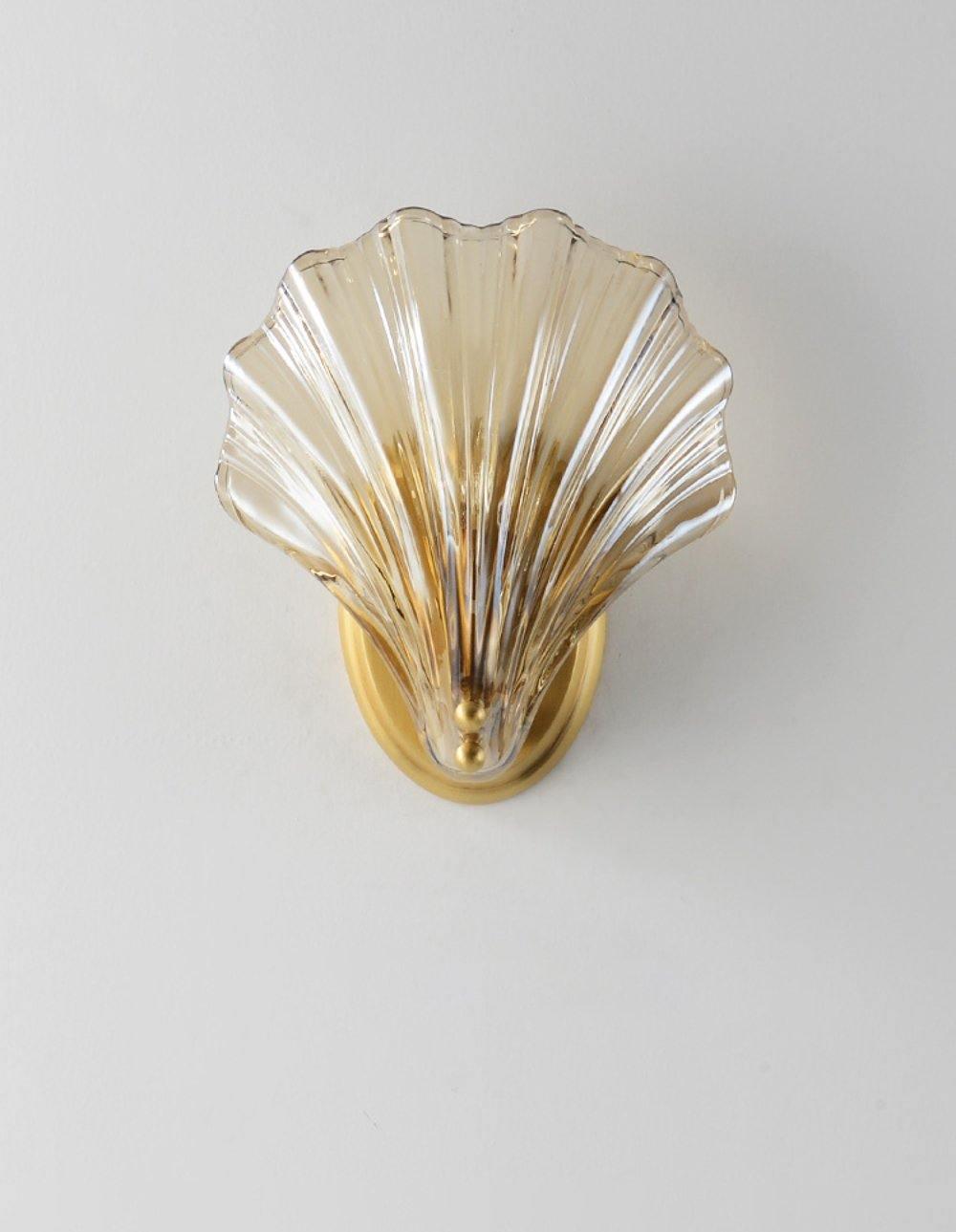 Photographed straight on, this Clérachic wall light's amber glass shell glows against a plain light grey wall.