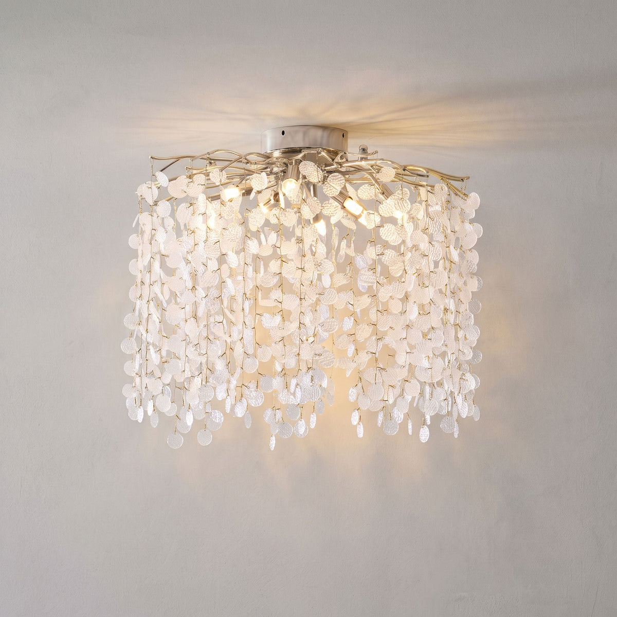 Mounted in a wall-ceiling corner, this Clérachic ceiling light glows against a plain grey wall, its frosted glass discs catching the light.