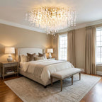 In a bedroom with French doors, this Clérachic ceiling light glows above a bed dressed in neutral linens and a patterned rug.