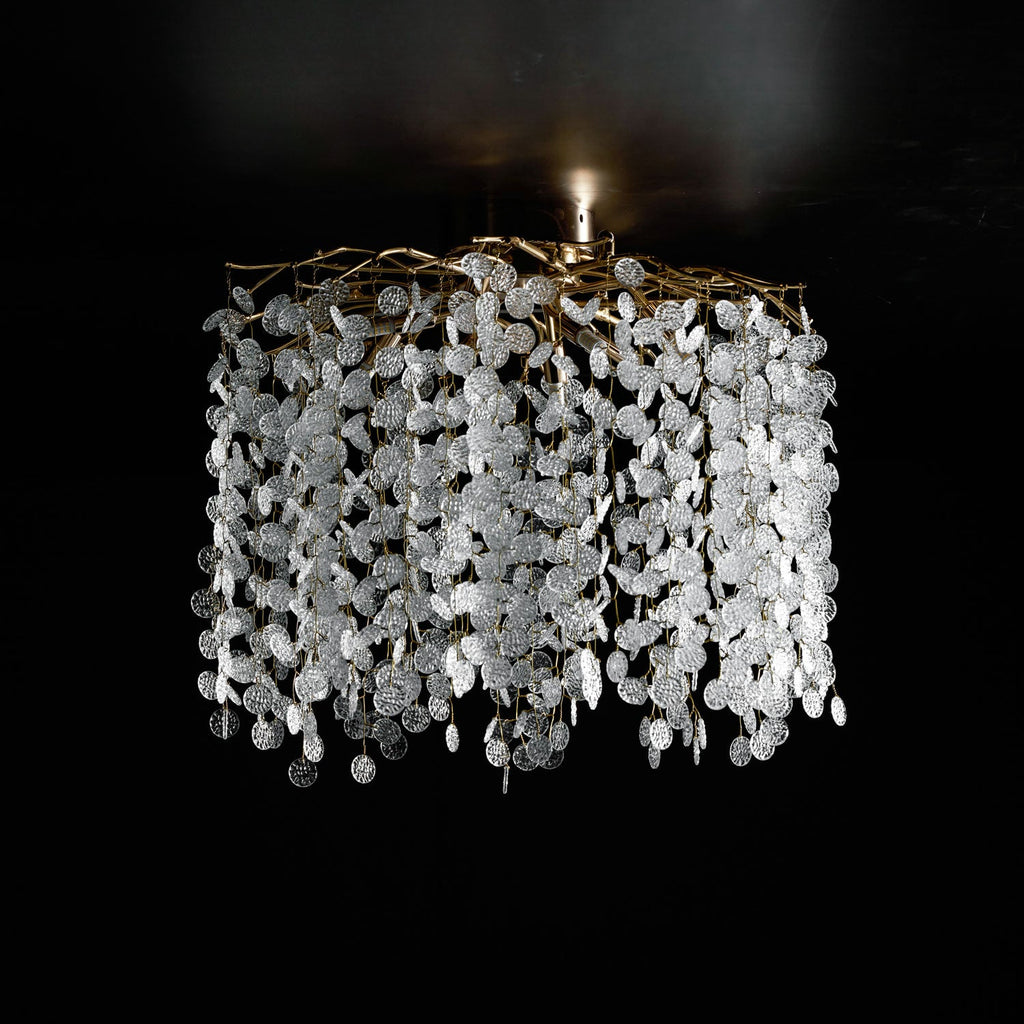 This Clérachic ceiling light in silver glows against a black background, its clear glass discs catching the light from above.