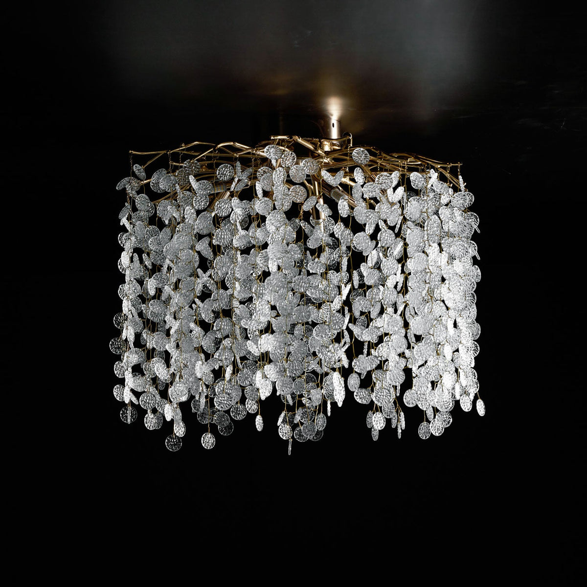 This Clérachic ceiling light in silver glows against a black background, its clear glass discs catching the light from above.