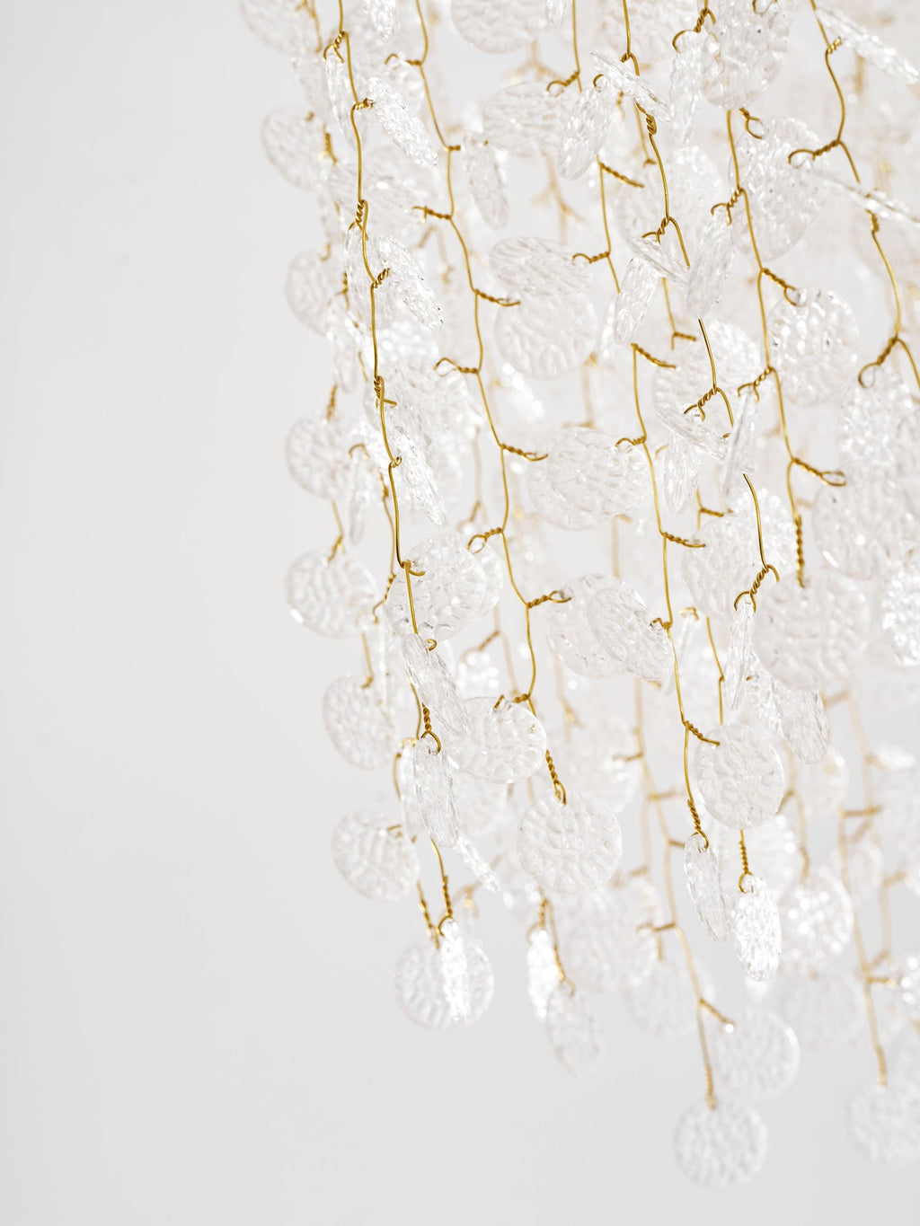 Close view of the gold branches and frosted glass discs cascading from this Clérachic ceiling light.