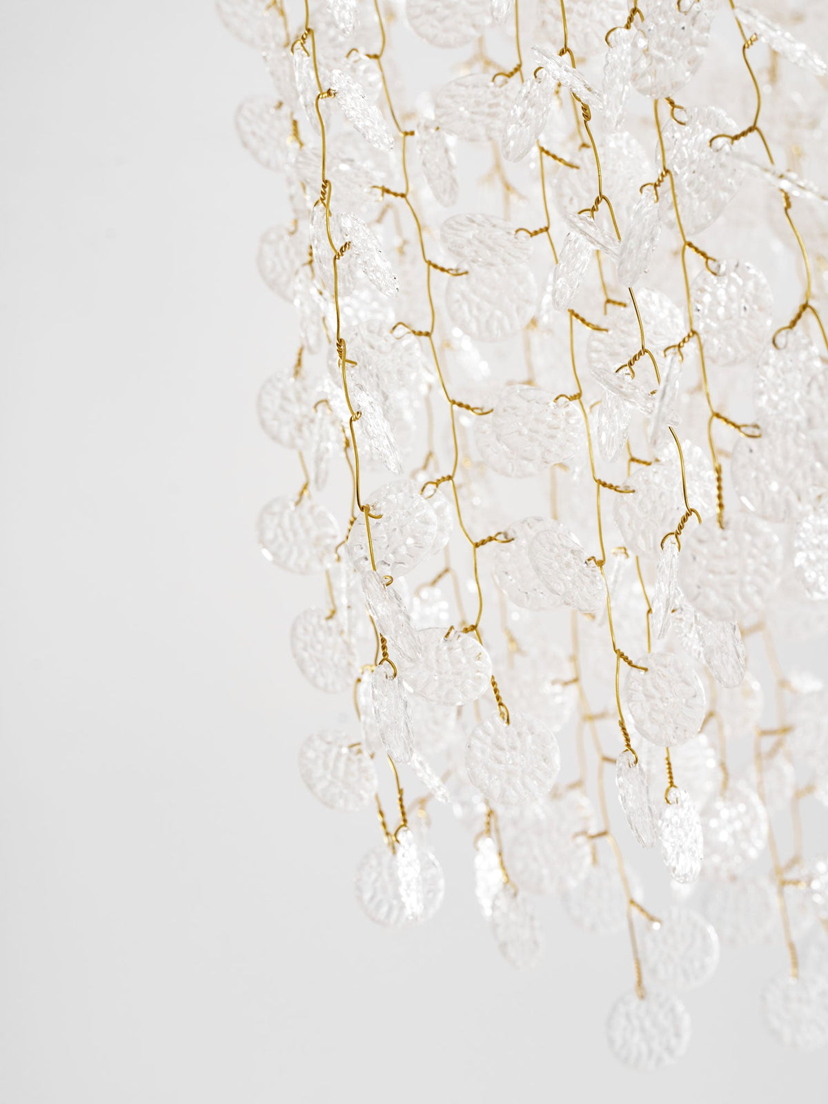 Close view of the gold branches and frosted glass discs cascading from this Clérachic ceiling light.