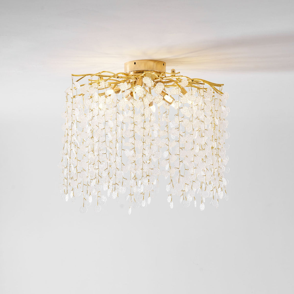 From a different low angle, this Clérachic ceiling light shows its mounting plate and cascading frosted glass discs on white.