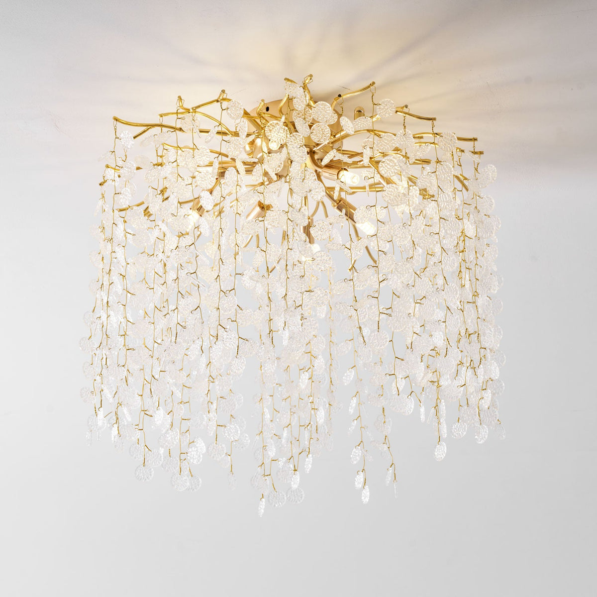 Viewed from an angle against a white background, this Clérachic ceiling light cascades its frosted glass discs from gold branches.