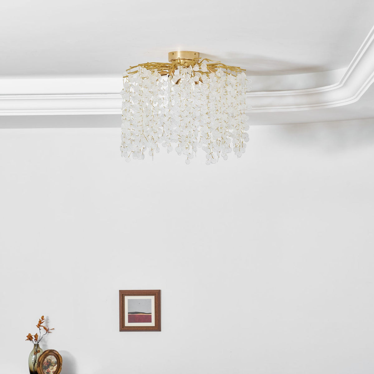 Mounted beside crown moulding on a plain white wall, this Clérachic ceiling light hangs above a small framed print.