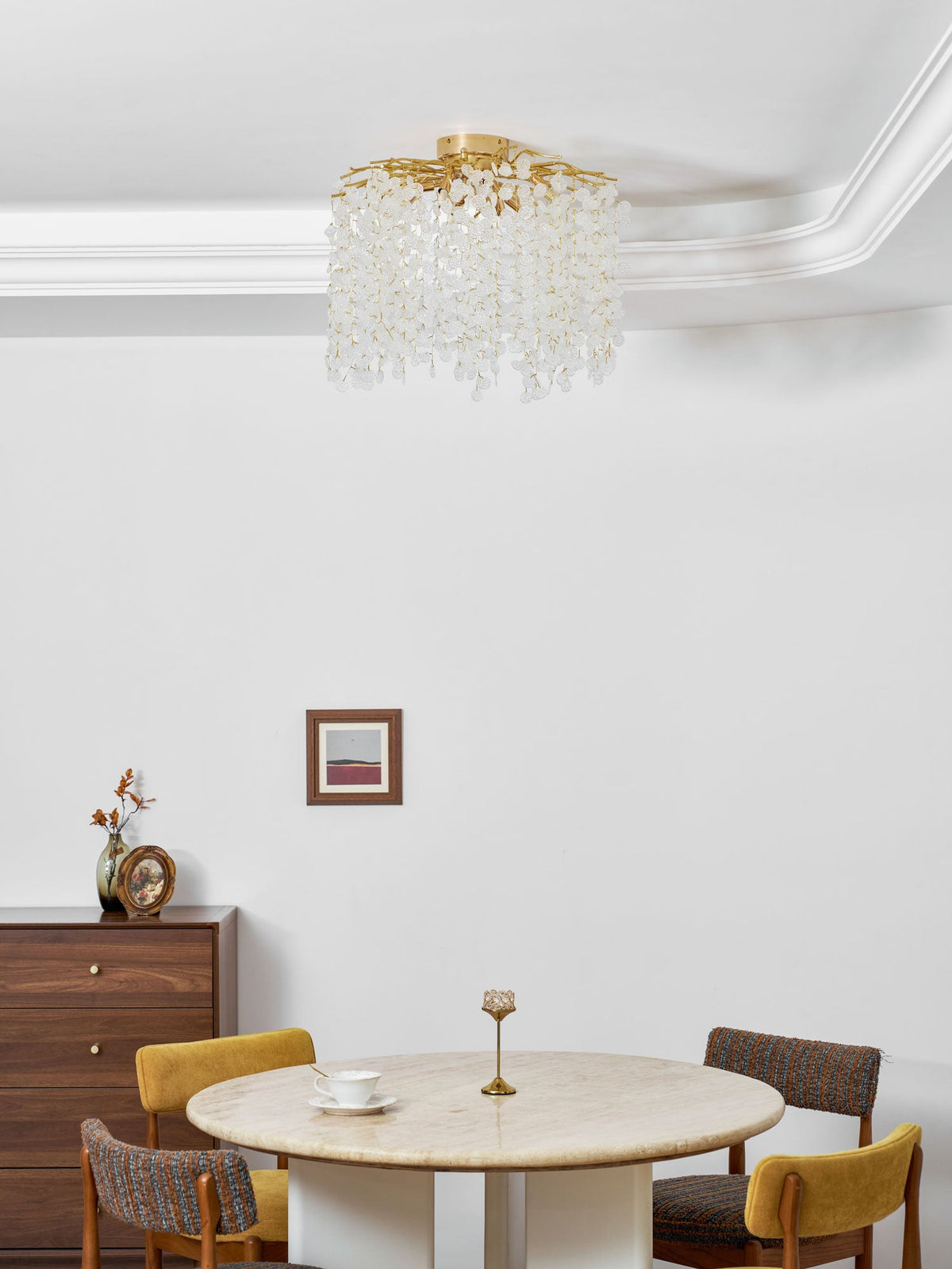 This Clérachic ceiling light hangs from a corniced ceiling above a dining room with a round marble table and patterned chairs.