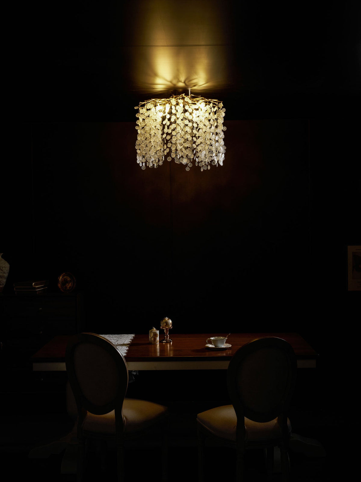 This Clérachic ceiling light glows warmly above a dark wood table set for two, in a dimly lit dining room.