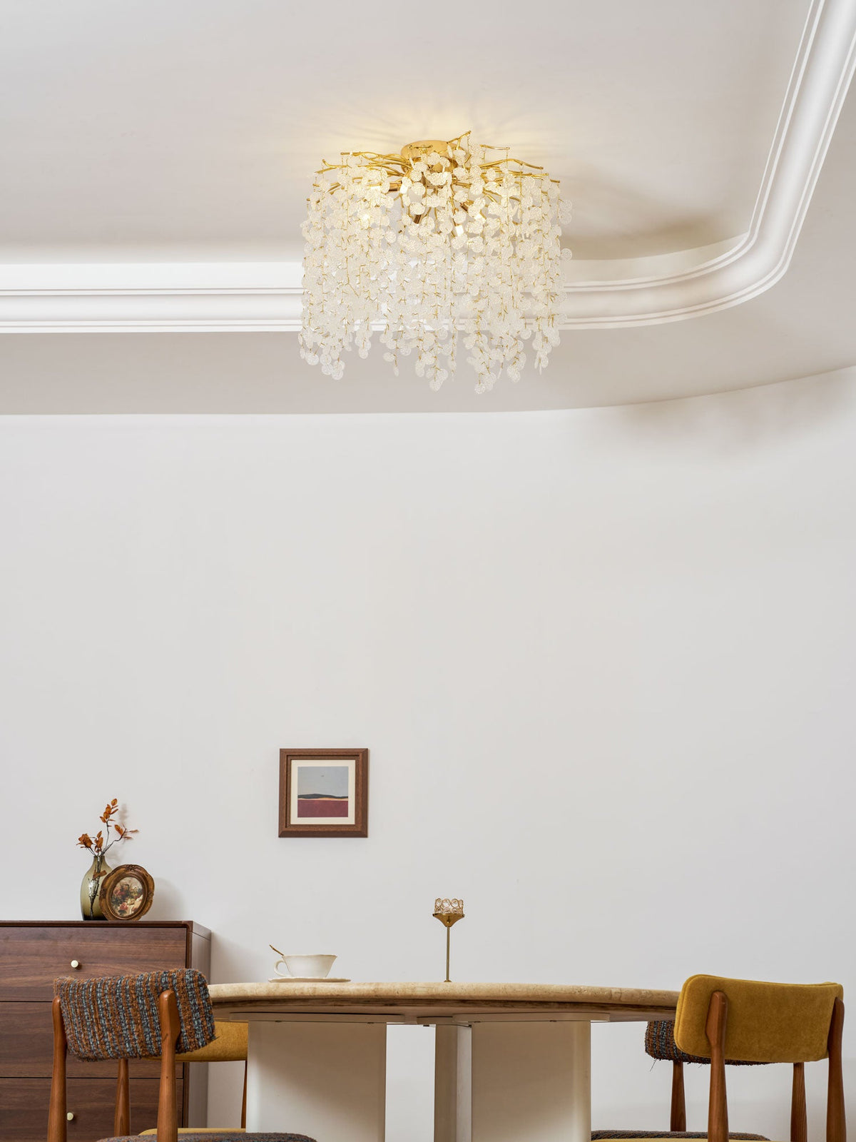 Seen close to the corniced ceiling, this Clérachic ceiling light hangs above a dining room with mustard-upholstered chairs.