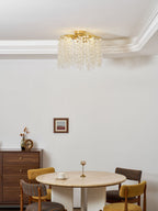 Framed by a dark wood sideboard, this Clérachic ceiling light hangs low over a round dining table with mustard chairs.