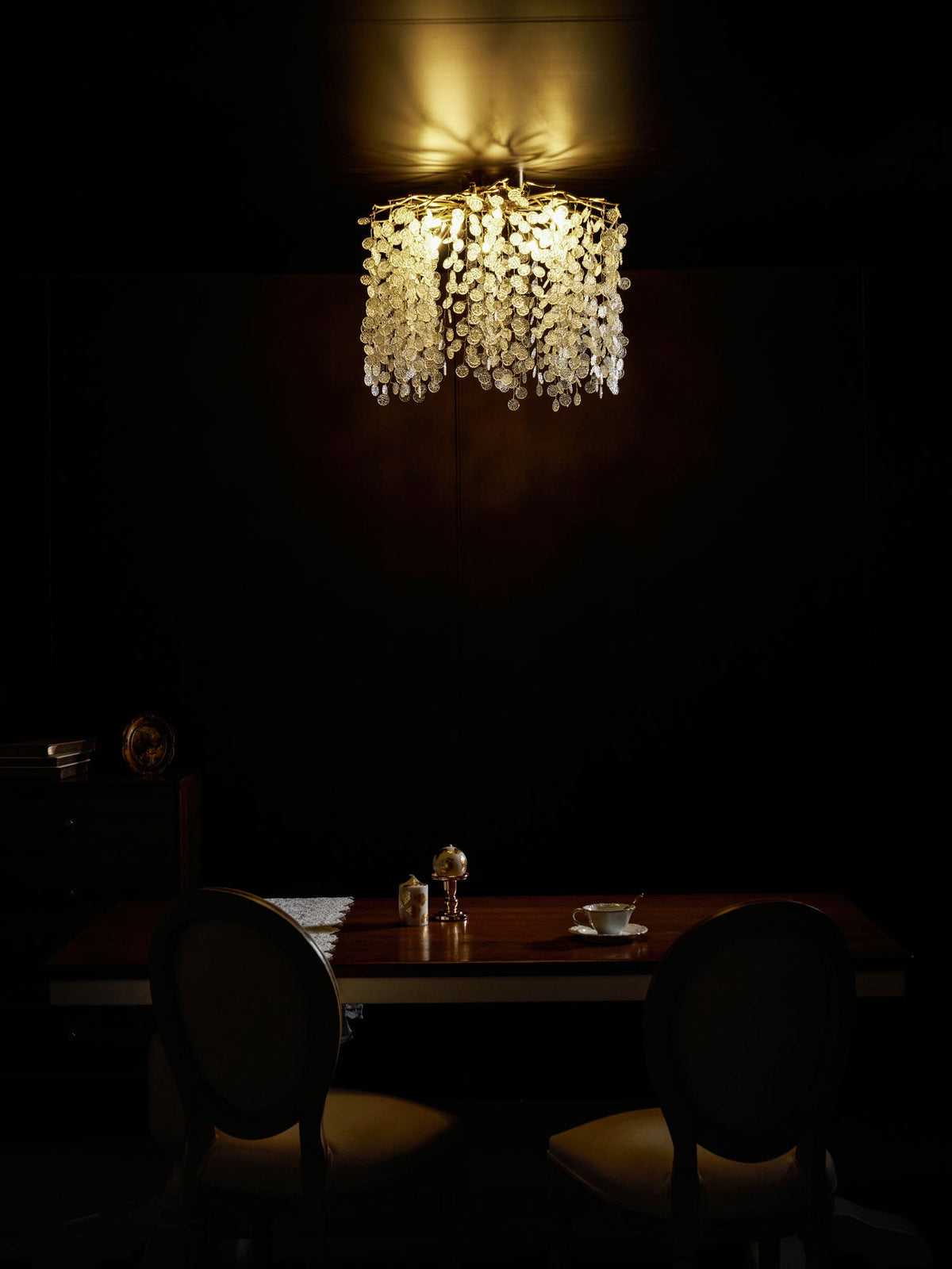 In a dimly lit dining room, this Clérachic ceiling light glows above a table set with salt and pepper shakers.