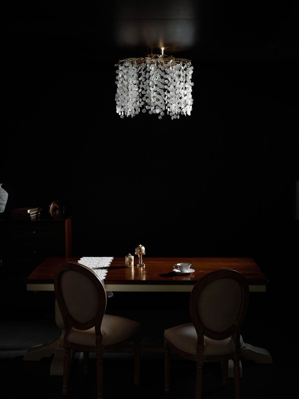 Closer to the table, this Clérachic ceiling light in silver glows above a setting of salt and pepper shakers and a teacup.