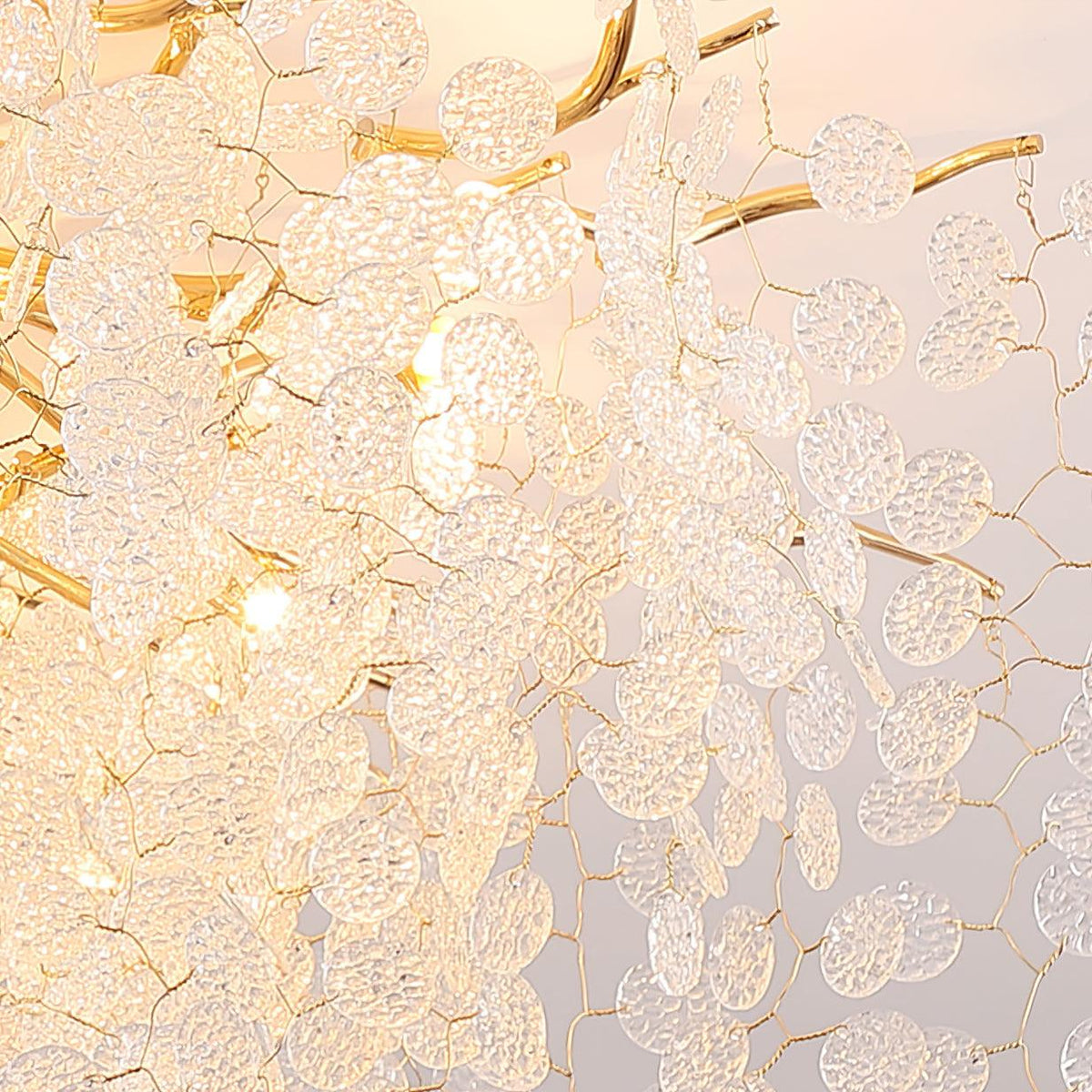 Close view of the frosted glass discs and gold branches on this Clérachic ceiling light, lit from within.