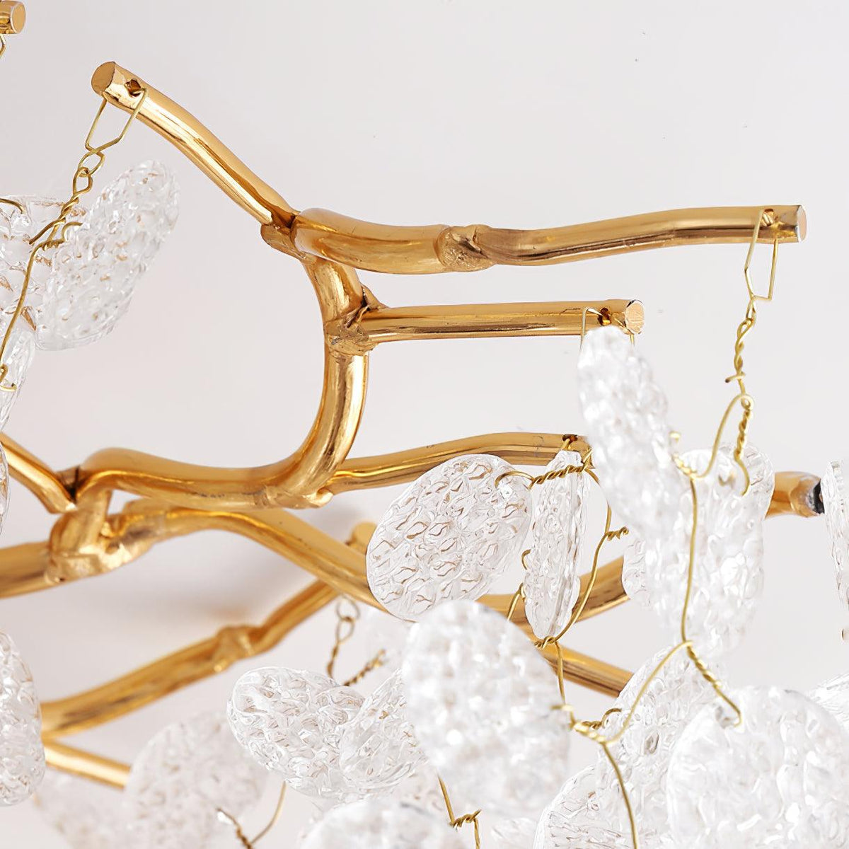 Close view of the cast aluminium gold branches and frosted glass discs on this Clérachic ceiling light, shown unlit on white.