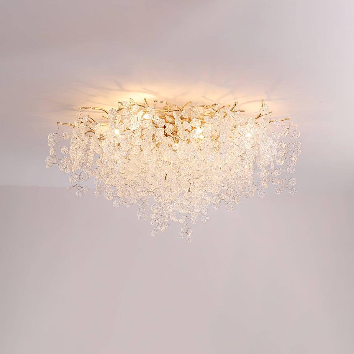 Close view of this Clérachic ceiling light glowing softly, its frosted glass discs catching the light against a pink-grey backdrop.