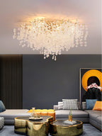 This Clérachic ceiling light glows above a grey sectional sofa in a living room with navy walls and brass coffee tables.