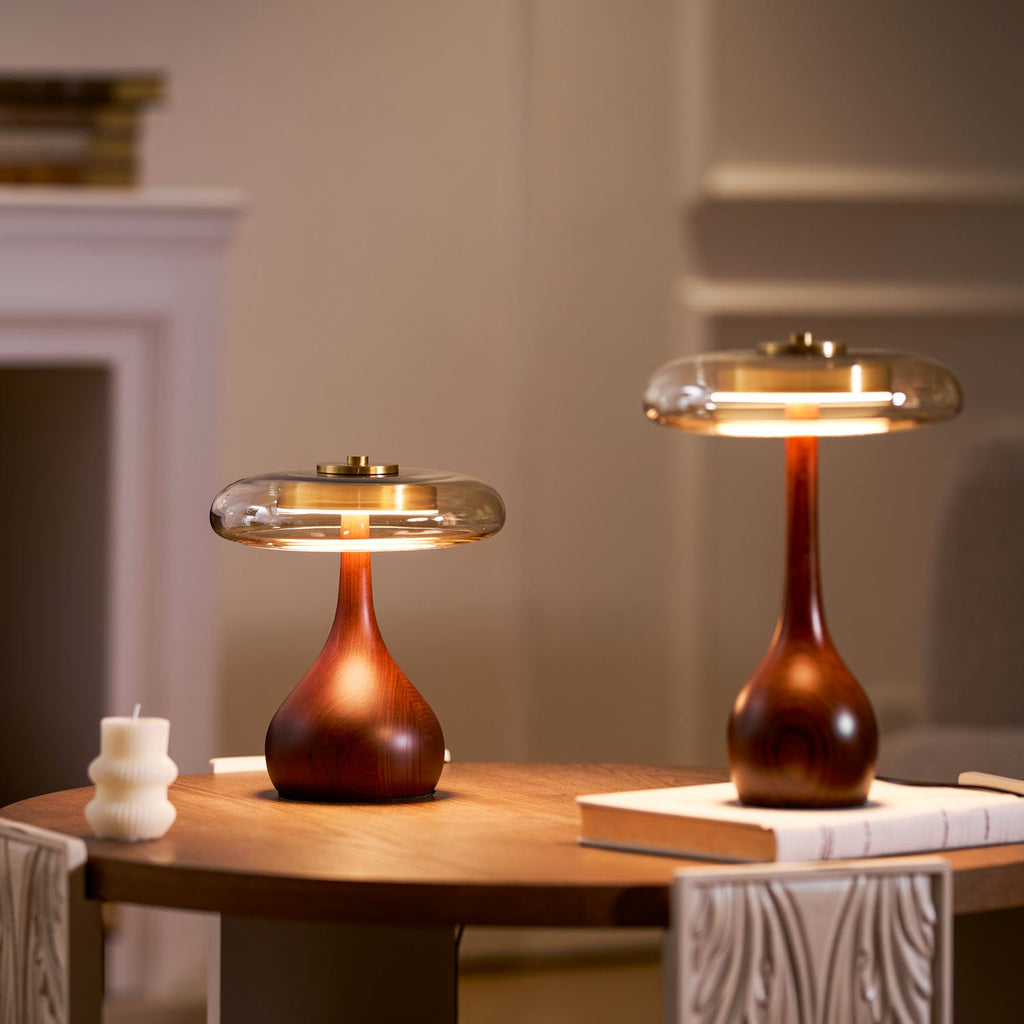 Tall amber glass table lamp lit warmly in a neutral space