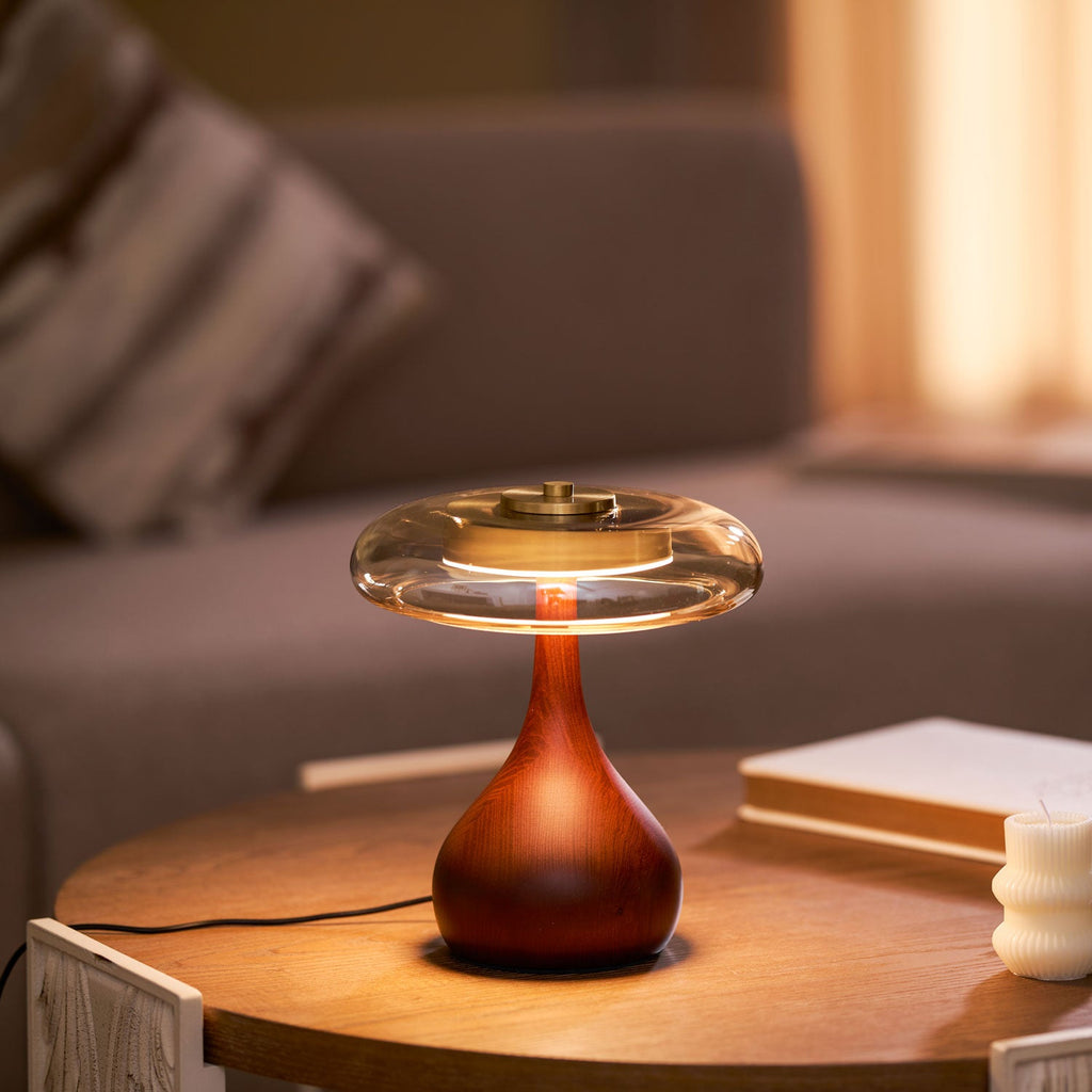 Wood base table lamp with glowing amber shade on a shelf