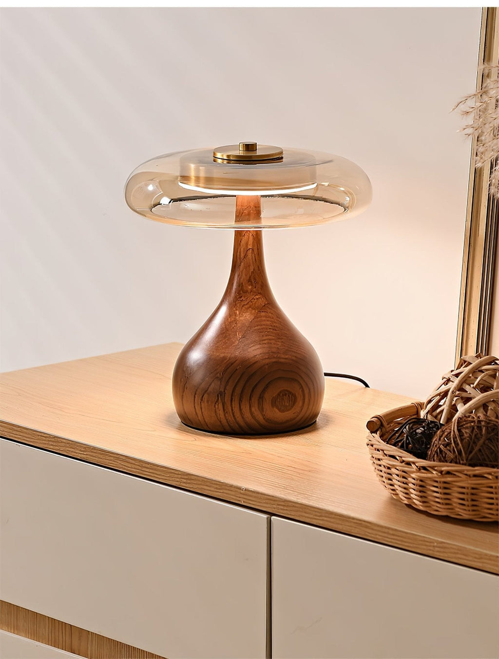 Walnut base table lamp lit warmly against a pale wall