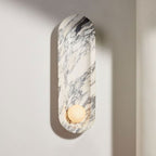 Natural light falls across the Clérachic wall sconce, its opal sphere unlit and its marble veining cast in shadow.