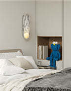 Beside a built-in bedside nook holding books and a small toy figure, the Clérachic wall light glows softly.