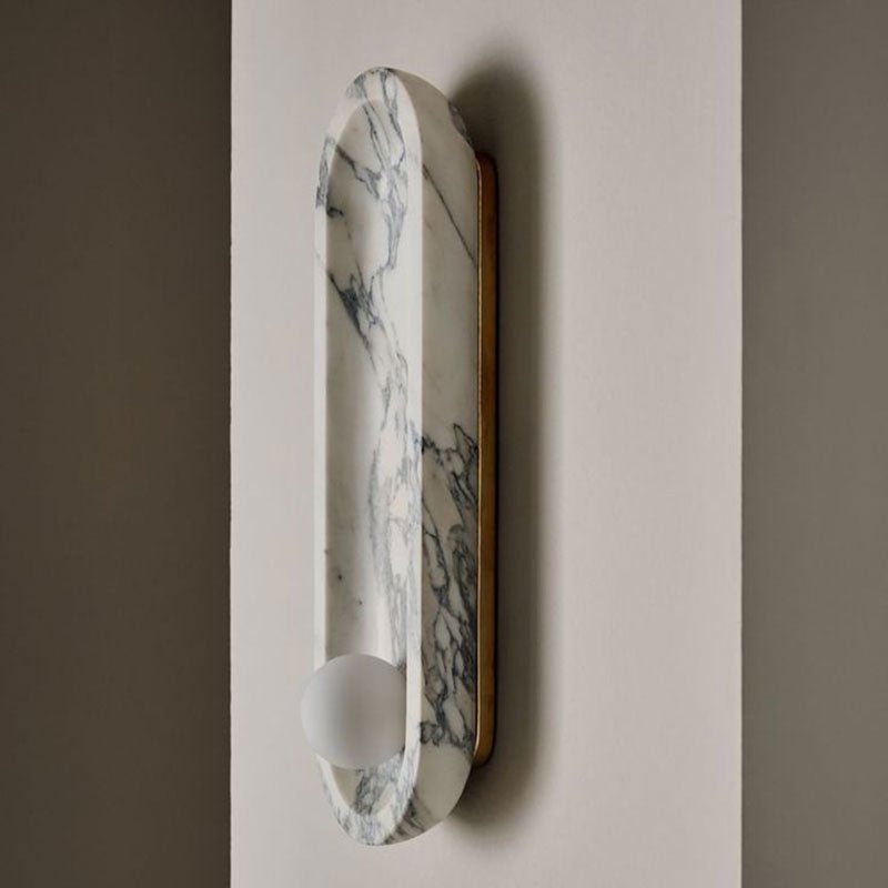 Another close angle on the Clérachic wall light's brass mounting edge, its marble form unlit against a beige wall.