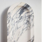 A tight crop on the Clérachic wall light's arched marble top shows its grey veining without the sphere in view.
