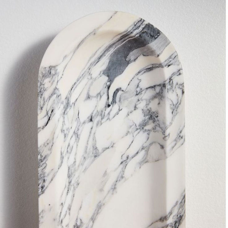 A tight crop on the Clérachic wall light's arched marble top shows its grey veining without the sphere in view.
