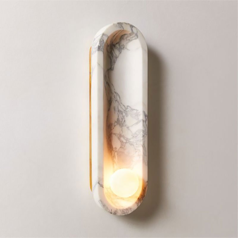 This side profile of the Clérachic wall light reveals its brass edge and the warm glow of its lit opal sphere.