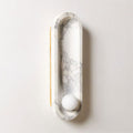 On a plain background, the Clérachic wall light shows its brass side edge beside the glowing frosted opal sphere.