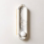 On a plain background, the Clérachic wall light shows its brass side edge beside the glowing frosted opal sphere.