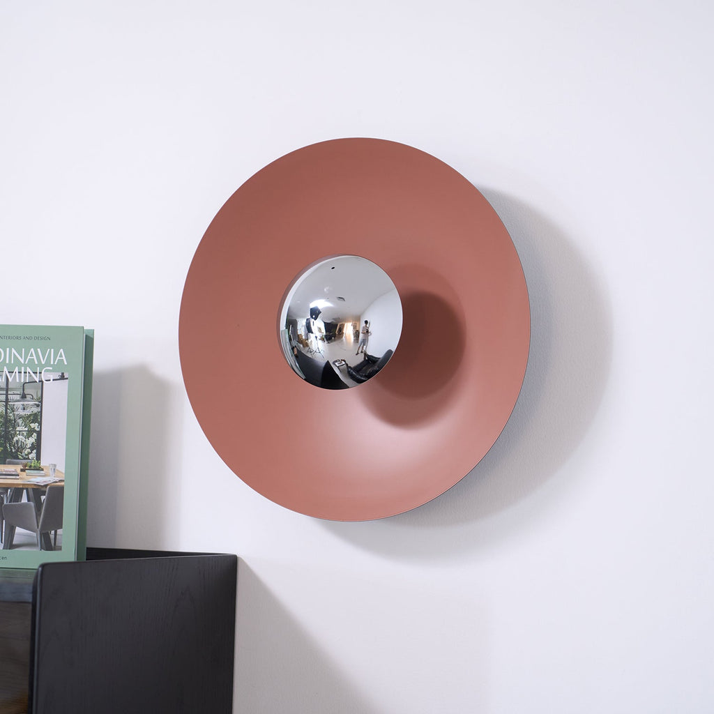 An unlit terracotta-toned version of this Clérachic wall light above a dark cabinet, its chrome centre plain and unlit.