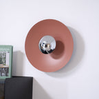 An unlit terracotta-toned version of this Clérachic wall light above a dark cabinet, its chrome centre plain and unlit.