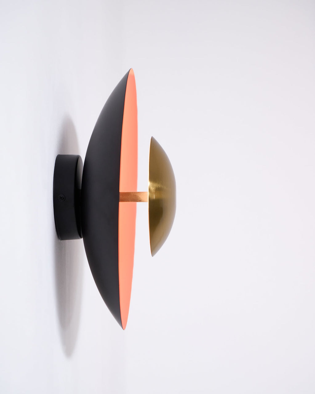 Side view of this Clérachic wall light on a white wall, showing its black mount arm and the slim edge of its shade.