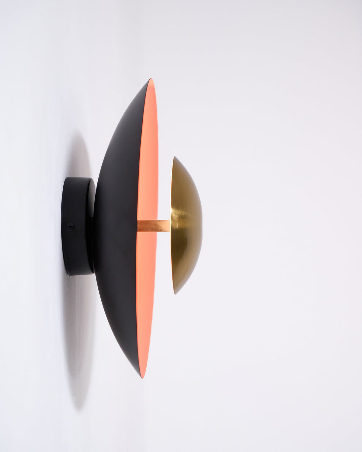 Side view of this Clérachic wall light on a white wall, showing its black mount arm and the slim edge of its shade.