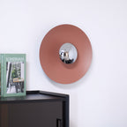 Closer view of the unlit terracotta wall light from Clérachic, its chrome centre catching daylight above a dark cabinet.