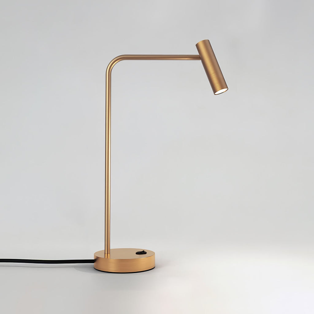 This gold Clérachic table lamp stands unlit in the studio, cord curling from its round base.