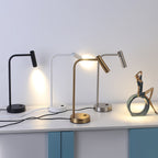 Four finishes of this Clérachic table lamp line up on a cabinet, one lit beside a small sculpture.