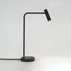 Cord curling from its round base, this black Clérachic table lamp stands unlit in the studio.