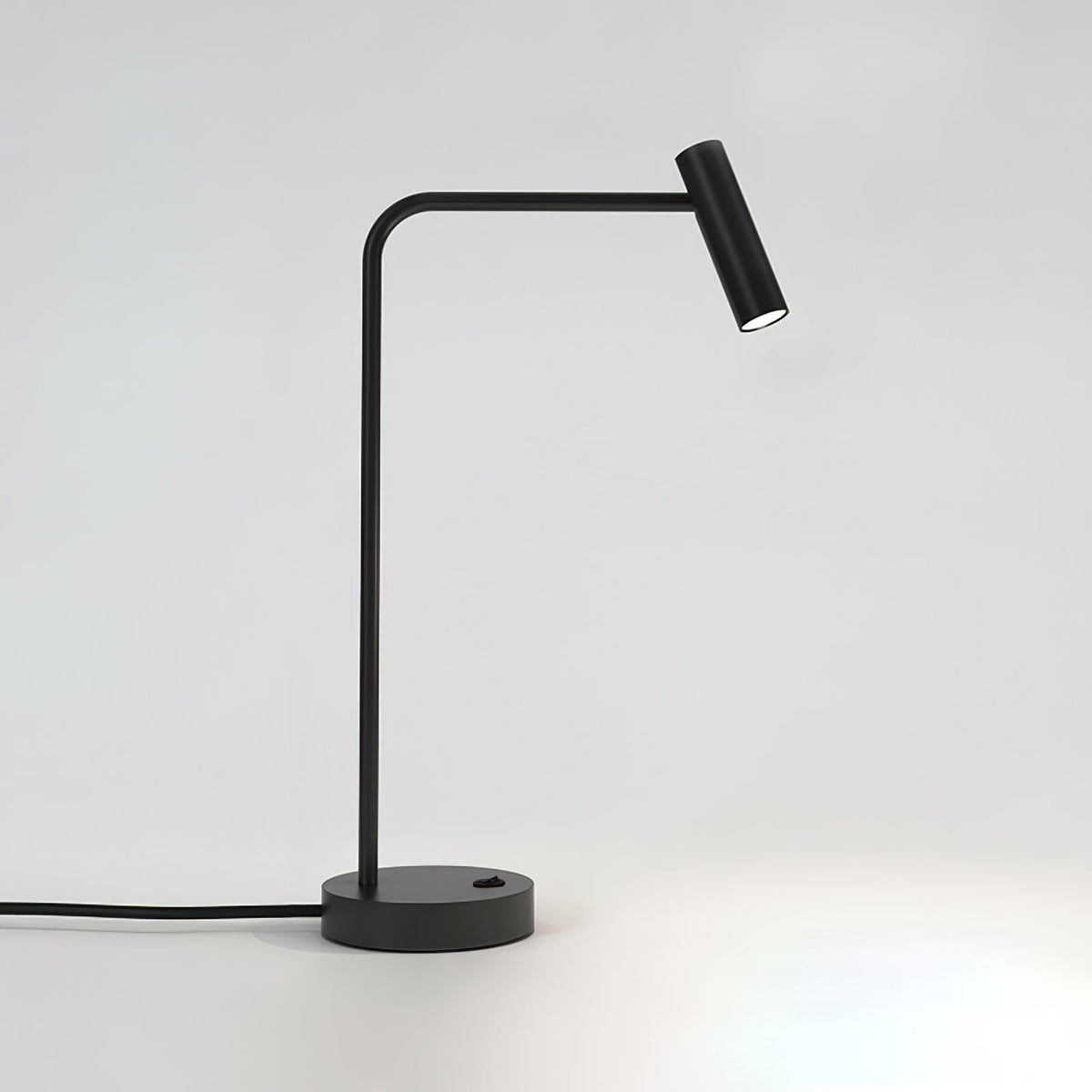 Cord curling from its round base, this black Clérachic table lamp stands unlit in the studio.