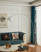 A close crop on the coffee table's whiskey tray sits beneath the Clérachic arc floor lamp's white dome shade over the teal sofa.