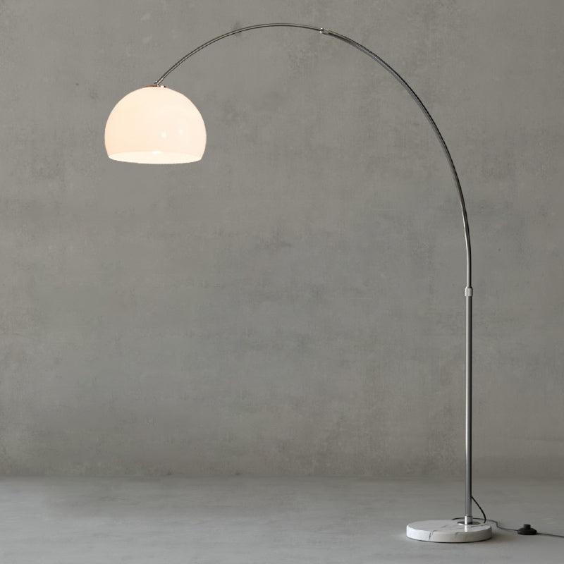 A close crop against the grey backdrop shows the curve of the Clérachic arc floor lamp's arm and white dome shade.