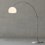 A close crop against the grey backdrop shows the curve of the Clérachic arc floor lamp's arm and white dome shade.