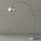 Set against the grey backdrop, a close crop follows the curve of the Clérachic arc floor lamp's arm and mirrored dome shade.