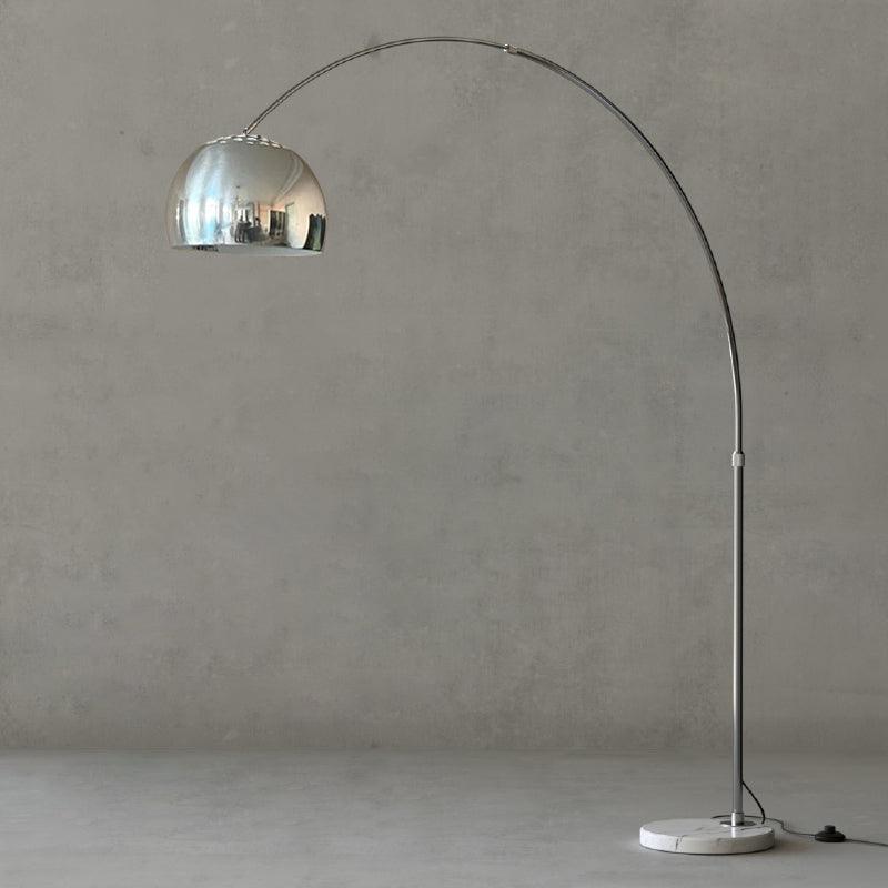 Set against the grey backdrop, a close crop follows the curve of the Clérachic arc floor lamp's arm and mirrored dome shade.