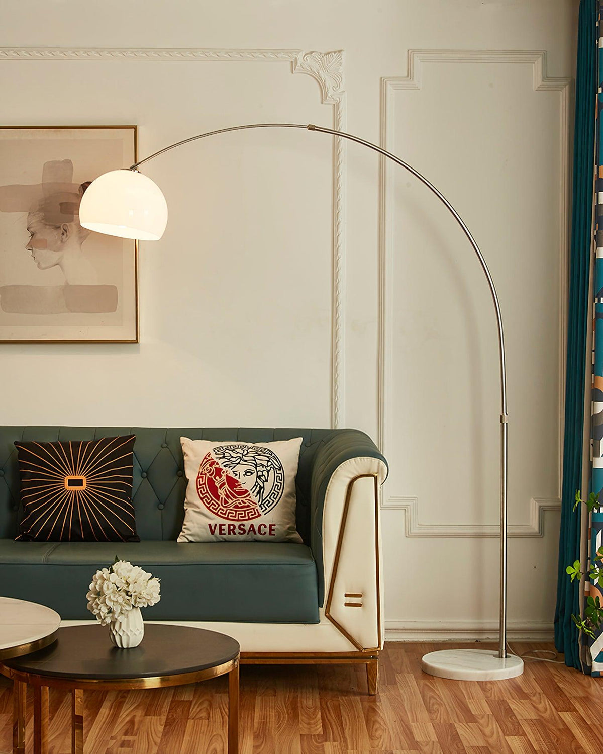 Framed to show the full room, the Clérachic arc floor lamp's white dome shade curves over a teal sofa with patterned curtains.