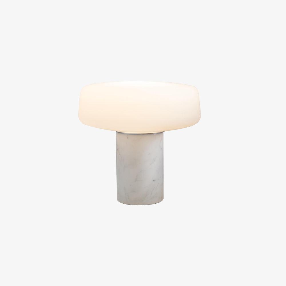Light catches the frosted shade of a white marble Clérachic table lamp glowing softly against a plain white studio background.
