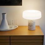Drinking glasses and a ceramic carafe rest on a tray beside a white marble Clérachic table lamp glowing on the sideboard.