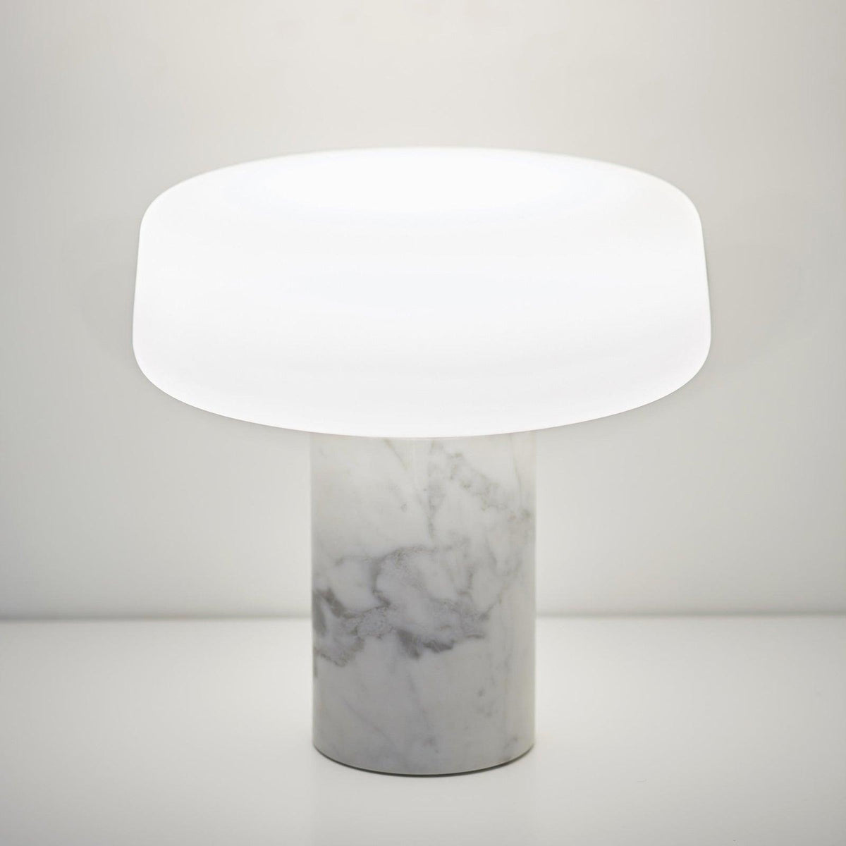 White marble Clérachic table lamp shown alone against a plain white background, its frosted glass shade catching the light.